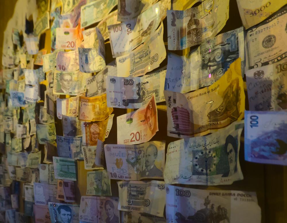 A photograph of bank notes from different countries, displayed on a wall.