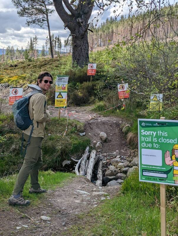A photograph of Harry Kuril hiking on a path with many warning signs ahead.